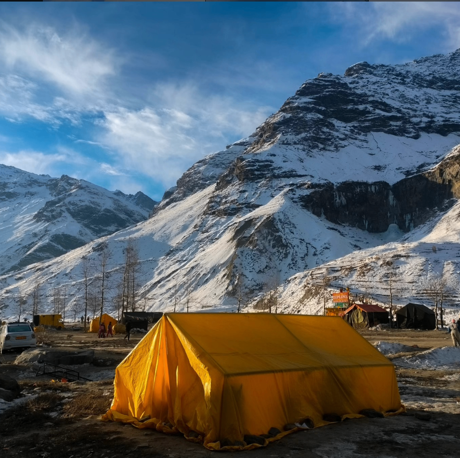 Yellow tent beneath snow-capped peaks