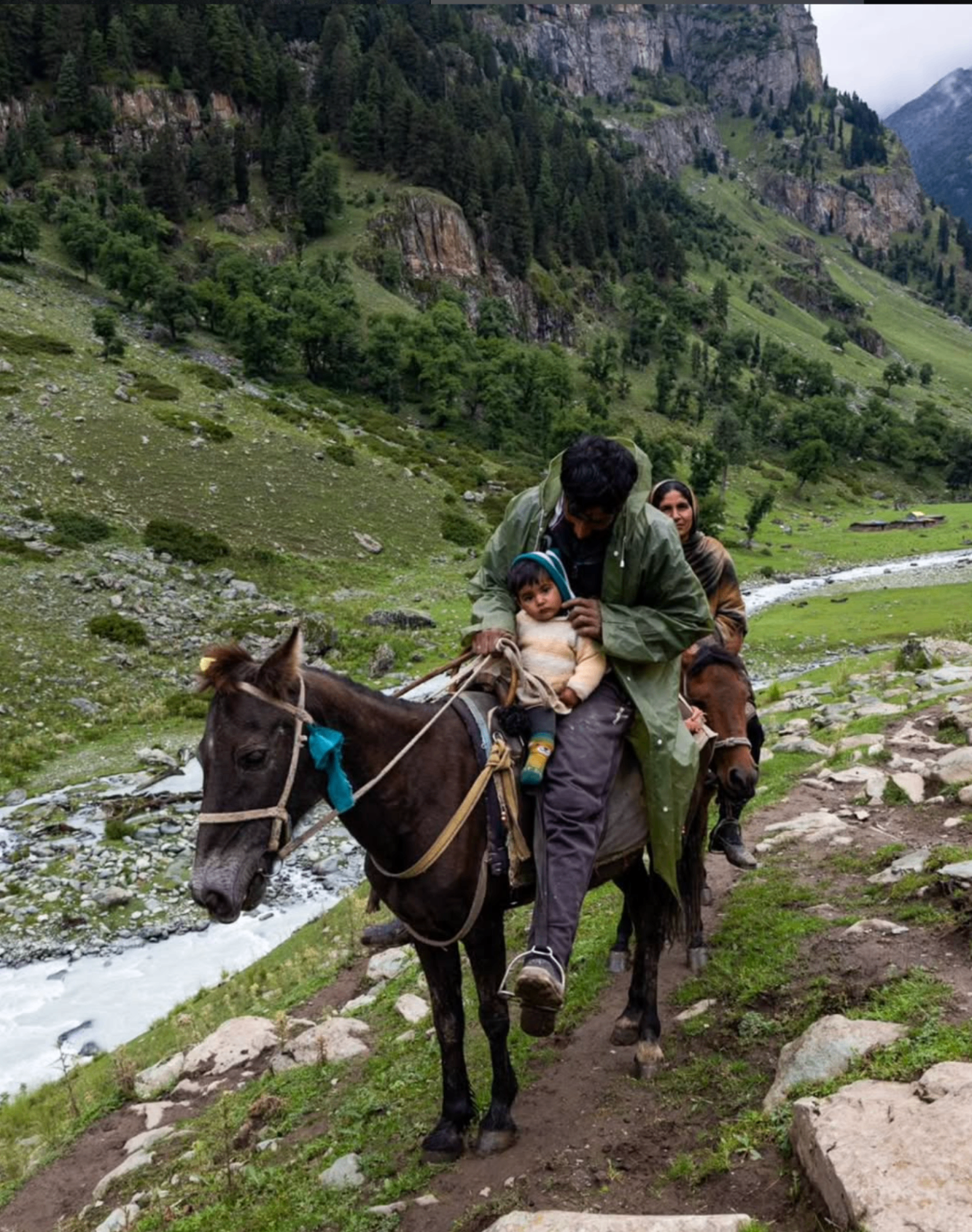 Family on horseback in a green valley